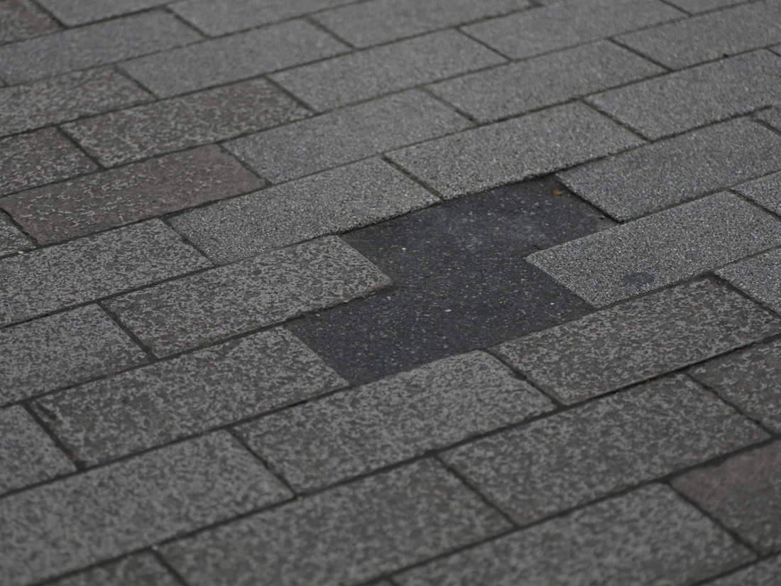 Asphalt shingle roof with a section of missing shingles exposing the layer beneath