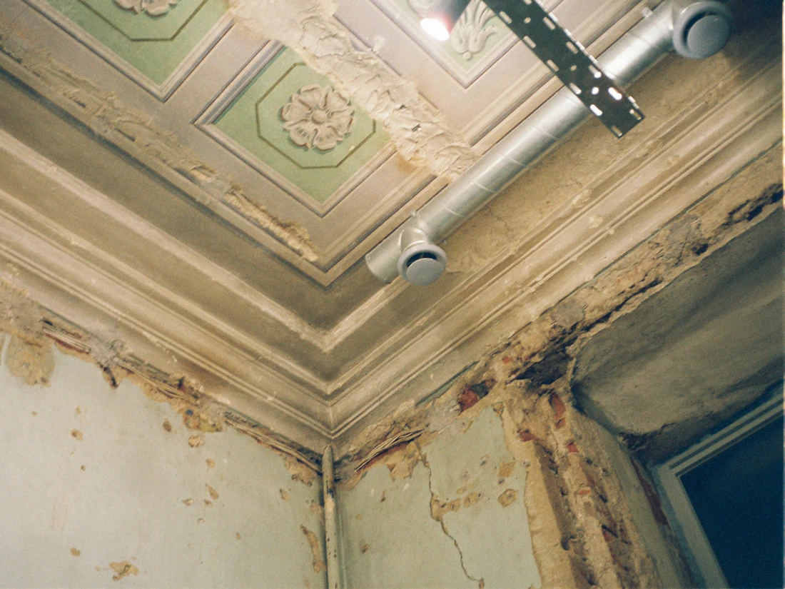 Water-stained ceiling corner with peeling paint from a roof leak